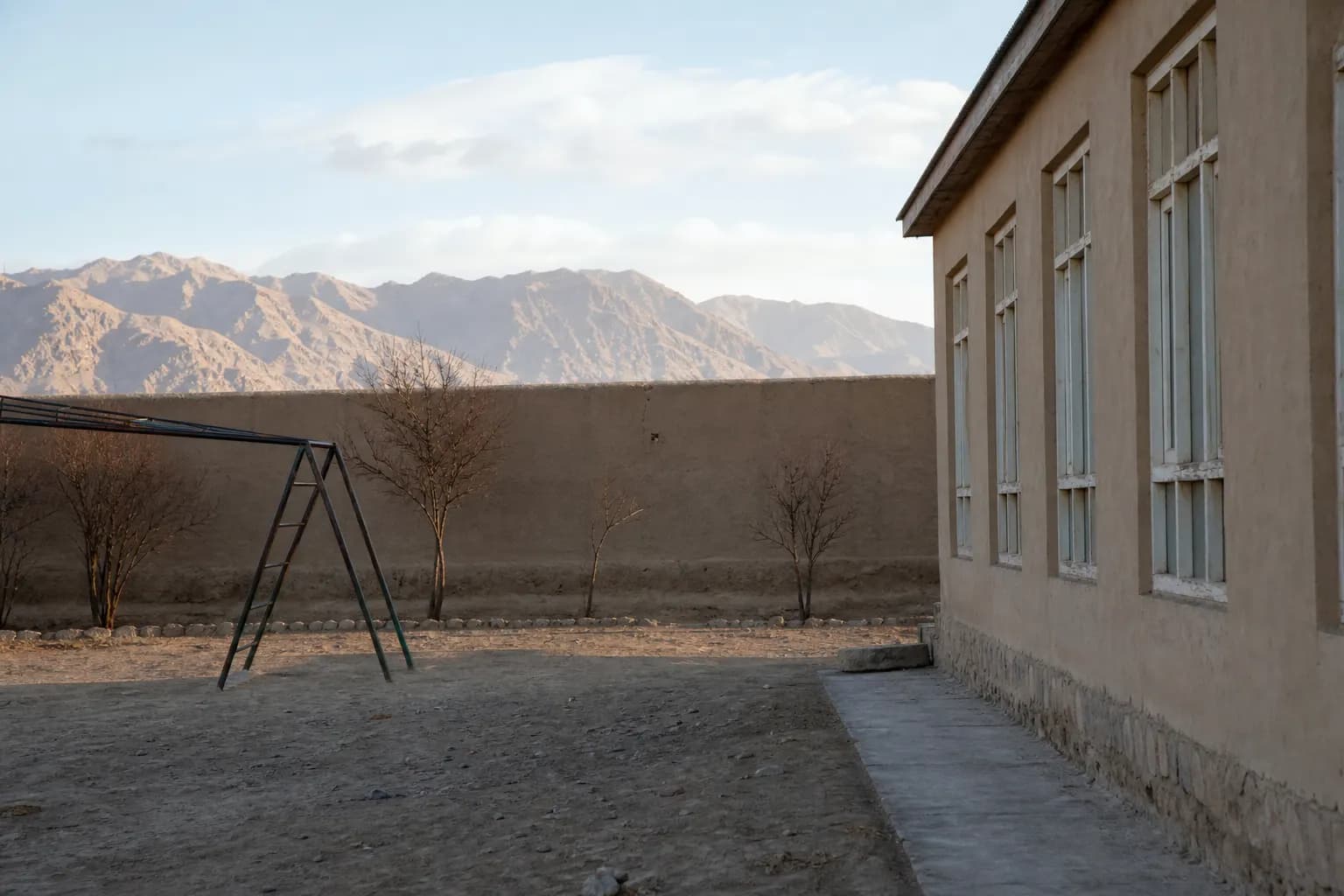 Quiet school courtyard in mountain light representing schools in Afghanistan today - watanchat.com education overview
